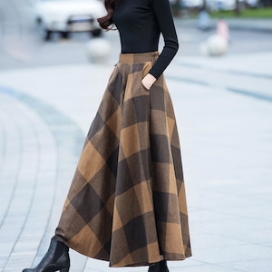 Peut inclure: Une jupe maxi &agrave; carreaux marrons et noirs avec une taille haute et des poches. La jupe est faite d'un tissu &eacute;pais et chaud, id&eacute;ale pour l'automne et l'hiver.