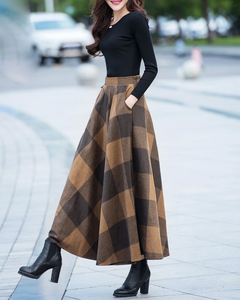 Peut inclure: Une jupe maxi &agrave; carreaux marrons et noirs avec une taille haute et des poches. La jupe est faite d'un tissu &eacute;pais et chaud, id&eacute;ale pour l'automne et l'hiver.