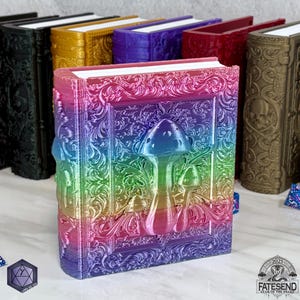 May include: An ornate, decorative book with a 3D design of mushrooms, featuring a rainbow colour scheme. The book is closed and has a white spine.
