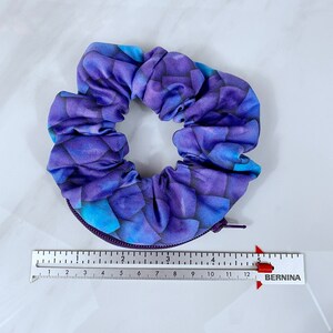 May include: Purple and blue patterned scrunchie with a zipper detail.