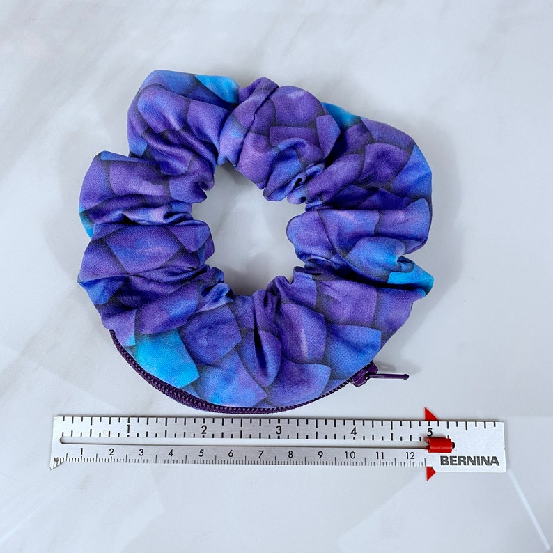 May include: Purple and blue patterned scrunchie with a zipper detail.