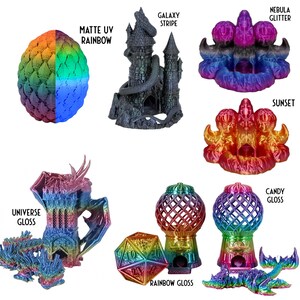 May include: A collection of 3D printed objects in various rainbow colors, including a dragon, a castle, a sphere, and a dice. The objects are printed in different finishes, including matte UV rainbow, galaxy stripe, nebula glitter, sunset, candy gloss, and rainbow gloss.
