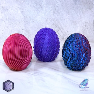 May include: Three dragon eggs, one is a deep purple with a scaly texture, one is a dark blue with a scaly texture, and one is a bright pink with a ribbed texture.