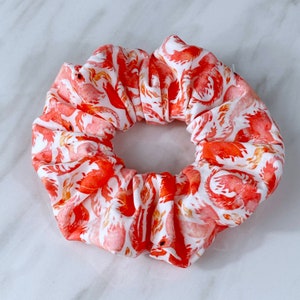 May include: A red and white patterned hair scrunchie with a floral design.
