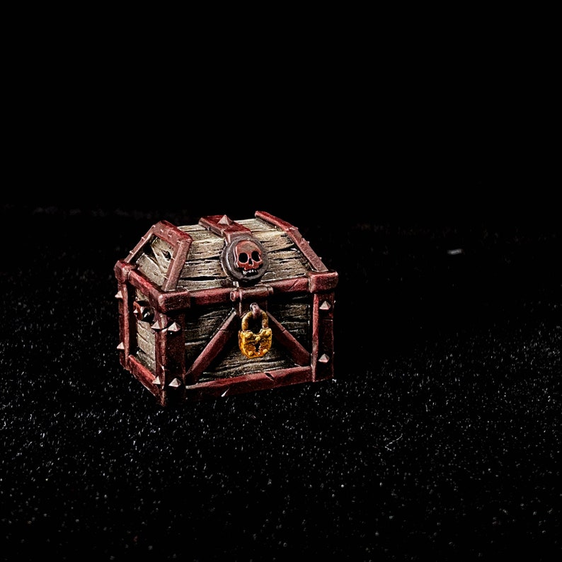 May include: A small wooden treasure chest with a skull and crossbones design on the lid. The chest is painted red and brown and has a gold padlock.