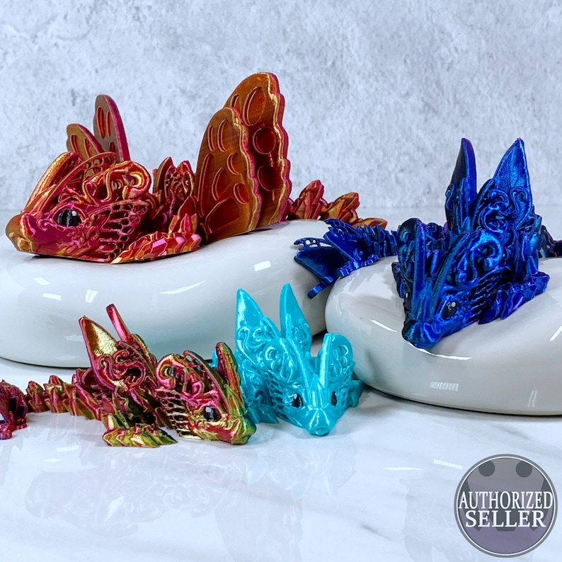 May include: Four intricately detailed dragon figurines, each with a unique iridescent finish. The dragons are posed in various positions, with wings spread and tails curled. The figurines are displayed on a white surface.