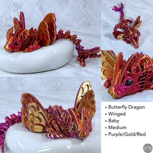 May include: A small, winged, purple, gold, and red butterfly dragon figurine. The dragon is in a curled up position with its wings spread out. The dragon is made of a 3D printed material.