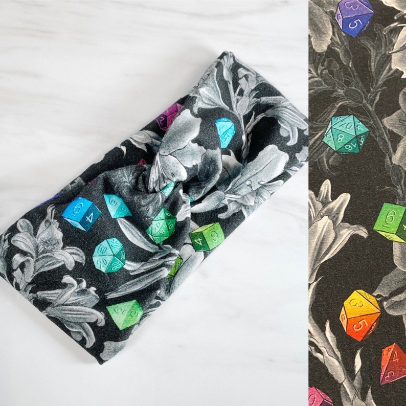 Puede incluir: Una diadema floral en blanco y negro con un patr&oacute;n repetido de dados y flores. Los dados son multicolores y tienen diferentes n&uacute;meros.