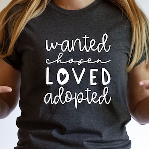 May include: Heather dark grey t-shirt with the text "wanted chosen loved adopted" in white with a small heart in the word "loved".