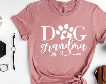 May include: A heather mauve t-shirt with the text "DOG grandma" in white with a paw print and heart in the "O".