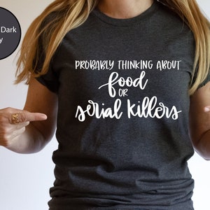 May include: A heather dark grey t-shirt with the text "Probably thinking about food or serial killers" in white lettering.