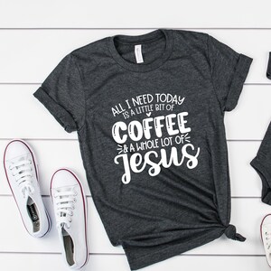 May include: Dark gray t-shirt and onesie set with the text "ALL I NEED TODAY IS A LITTLE BIT OF COFFEE & A WHOLE LOT OF JESUS" in white. White sneakers with red trim are also in the image. The set is a matching outfit.