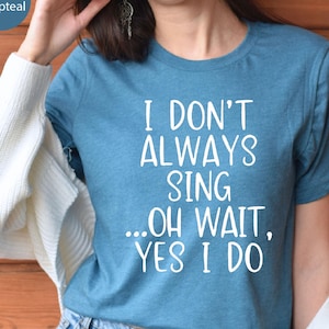 Op de afbeelding: Een heather deep teal t-shirt met korte mouwen en witte tekst die luidt I DON'T ALWAYS SING ...OH WAIT, YES I DO. Het shirt heeft een ronde hals en is gemaakt van een zachte, gemêleerde stof. Het ontwerp is gecentreerd op de voorzijde.