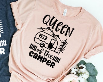 Könnte beinhalten: Zwei T-Shirts mit dem Text "Queen of the Camper" und einer Grafik eines Wohnmobils. Das Shirt links ist marineblau und das Shirt rechts ist pfirsichfarben.