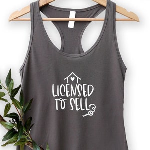 May include: A dark gray tank top with a white graphic that says "Licensed to Sell" with a house and key design.