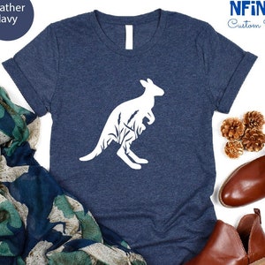 May include: A heather navy blue t-shirt with a white silhouette of a kangaroo with a joey in its pouch. The kangaroo is surrounded by a design of leaves and branches. The text "NFINITI Custom Shirts" is in the top right corner of the image.