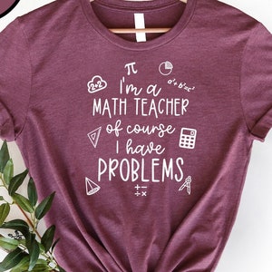 May include: Heather maroon t-shirt with a white graphic that says "I'm a math teacher of course I have problems" with math symbols surrounding the text.