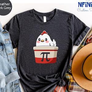 May include: Heather dark gray t-shirt featuring a cartoon chicken in a pie crust with the pi symbol. The shirt has a crew neck and short sleeves. The text "NFINTI Custom Shirts" is in the upper right corner.
