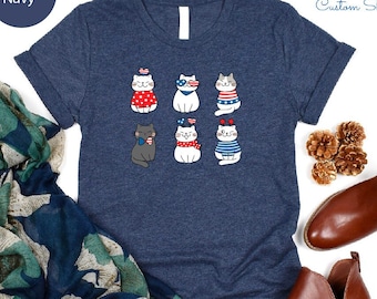 May include: A navy blue t-shirt with a graphic of six cats wearing red, white, and blue patriotic accessories. The text "NFINITI Custom Shirts" is in the top right corner of the image.