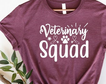 May include: Heather maroon t-shirt with white text that reads "Veterinary Squad" with a paw print and stethoscope graphic.