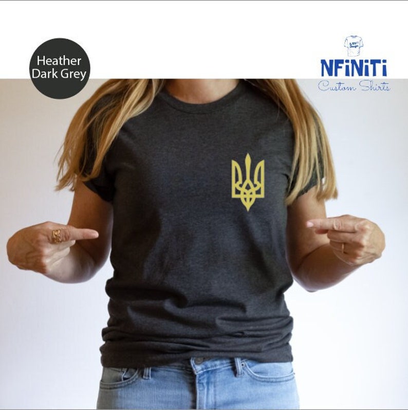 May include: A heather dark grey t-shirt with a gold embroidered Ukrainian trident symbol. The shirt is being modeled by a person. The text "NFINITI Custom Shirts" is visible in the top right corner of the image.