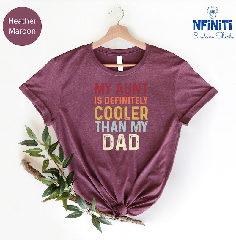 May include: Heather maroon t-shirt with the text "My Aunt is Definitely Cooler Than My Dad" in a retro rainbow color scheme.