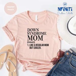 Puede incluir: Una camiseta rosa con el texto "Down Syndrome Mom (noun) 1. Like a regular mom but cooler."