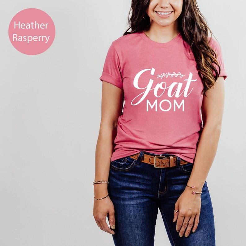 May include: A pink heather raspberry t-shirt with the text "Goat Mom" in white lettering with a small floral design above the word "Goat".