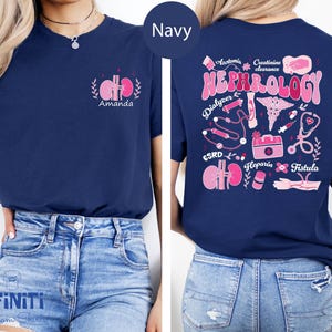 Op de afbeelding: Marineblauw T-shirt met een roze nierafbeelding en de naam "Amanda" op de voorkant. De achterkant toont het woord "Nefrologie" in roze, samen met medische illustraties en termen als "Dialyzer" en "Fistula".