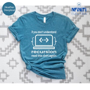 Pode incluir: Camiseta azul-petróleo com o texto branco "if you don't understand recursion read this shirt again". O design inclui um laptop com símbolos de código. A camisa é amarrada na parte inferior.