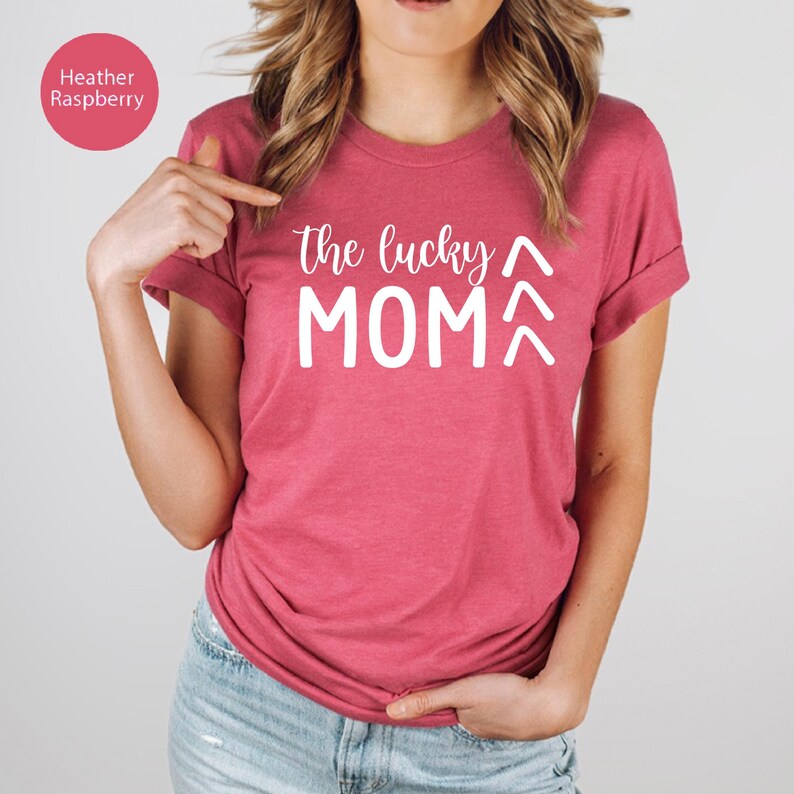 May include: Heather raspberry-colored t-shirt with the text "the lucky MOM" in white. The shirt has short sleeves and a crew neck. The text is centered on the front of the shirt. The shirt is made of a soft material.