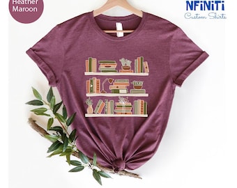 May include: A heather maroon t-shirt with a graphic of a bookshelf filled with books and plants. The text "NFINITI Custom Shirts" is in the top right corner of the image.