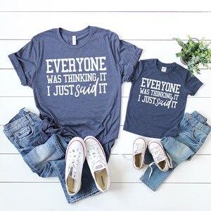 Pode incluir: Camisetas combinando azul marinho com texto branco. A camiseta de adulto diz "Everyone was thinking, it I just said it". A camiseta de crian&ccedil;a diz "Everyone was thinking, it I just said it".