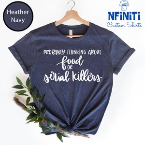 May include: A heather navy blue t-shirt with the text "Probably thinking about food or serial killers" in white script.