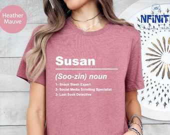 Può includere: Maglietta color malva heather con testo bianco che recita "Susan (Soo-zin) nome 1- Esperta di nascondigli per snack 2- Specialista nello scorrimento dei social media 3- Detective di calzini persi"