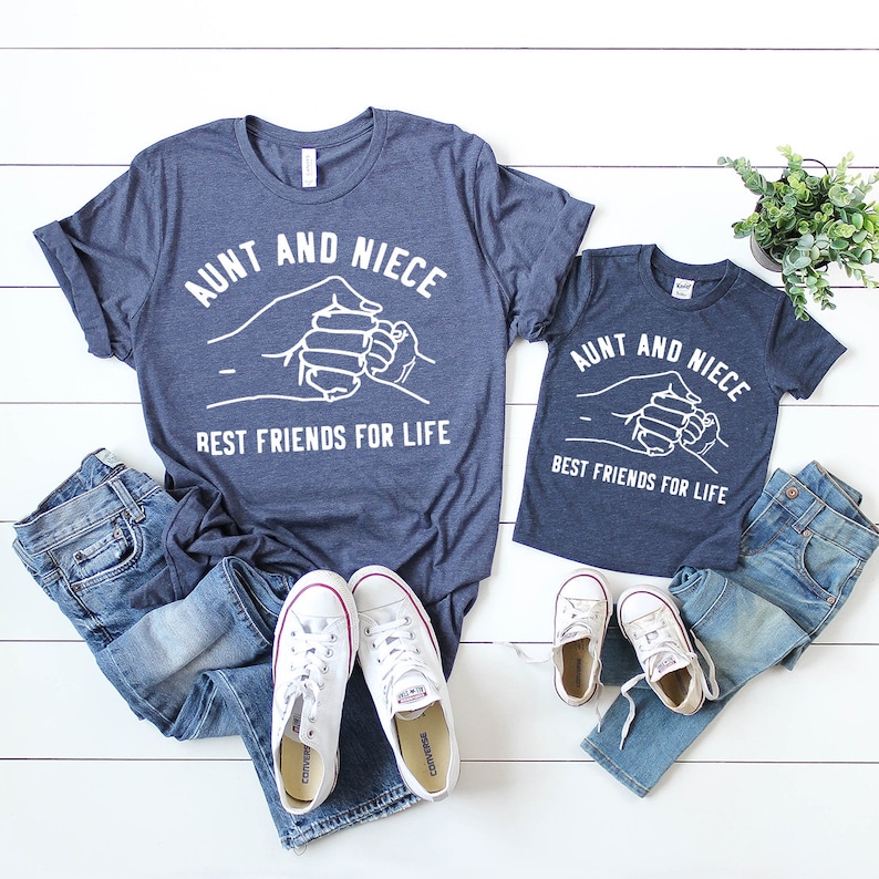 Pu&ograve; includere: Due magliette blu navy con testo bianco e un'immagine di due mani intrecciate. Il testo sulle magliette recita "Zia e nipote Migliori amiche per la vita".