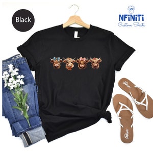 a black t - shirt with three cows on it