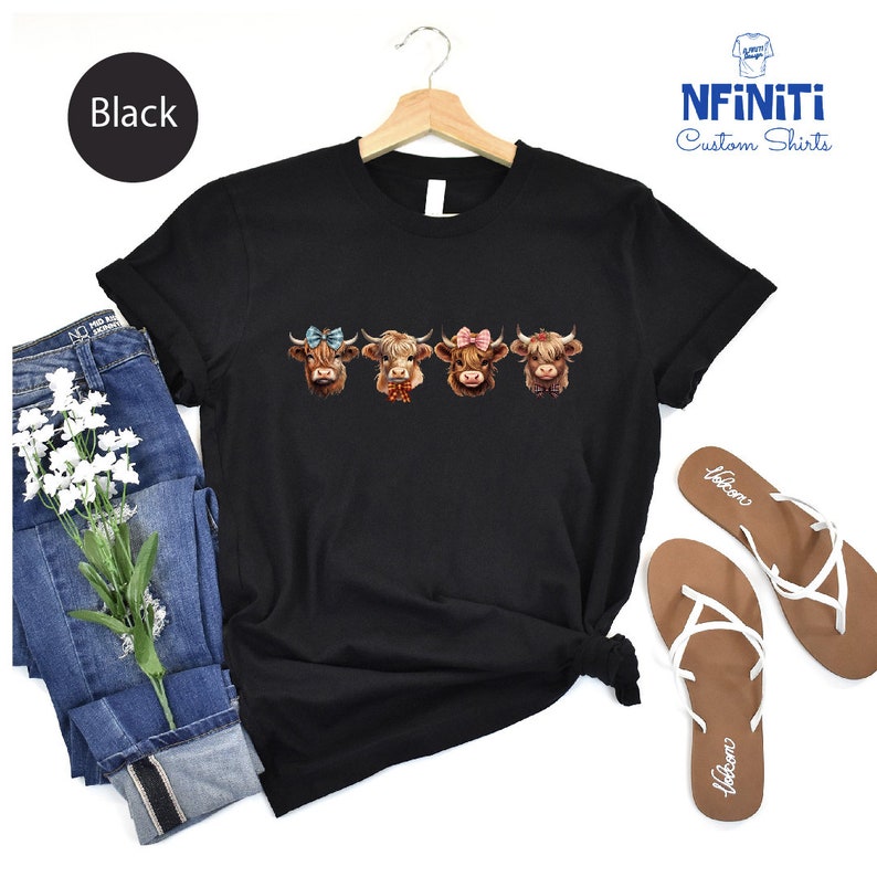 a black t - shirt with three cows on it
