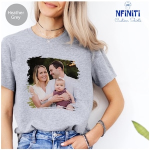 May include: Heather grey t-shirt with a photo of a family of three. The photo is printed on the shirt in a distressed style.