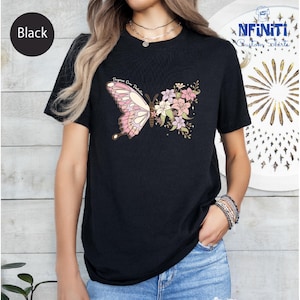 Puede incluir: Camiseta negra con diseño de mariposa. La mariposa tiene alas rosas y blancas con el texto "Progress Over Perfection". El otro lado de la mariposa está hecho de flores rosas, blancas y verdes. Cuello redondo.
