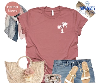 Könnte beinhalten: Ein T-Shirt in Heide-Mauve mit einem weißen Palmenbaum-Motiv. Das Shirt wird mit Jeans-Shorts, einer Strohtasche mit einem rosa Quasten und weißen Sandalen kombiniert. Der Text "NFNITI Custom Shirts" ist in der oberen rechten Ecke des Bildes sichtbar.