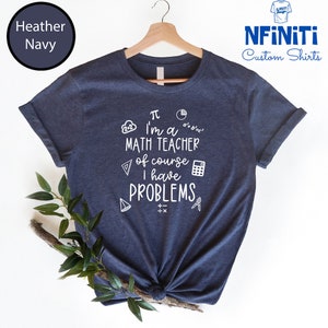 May include: A navy blue t-shirt with a white graphic that says "I'm a math teacher of course I have problems" with math symbols surrounding the text.