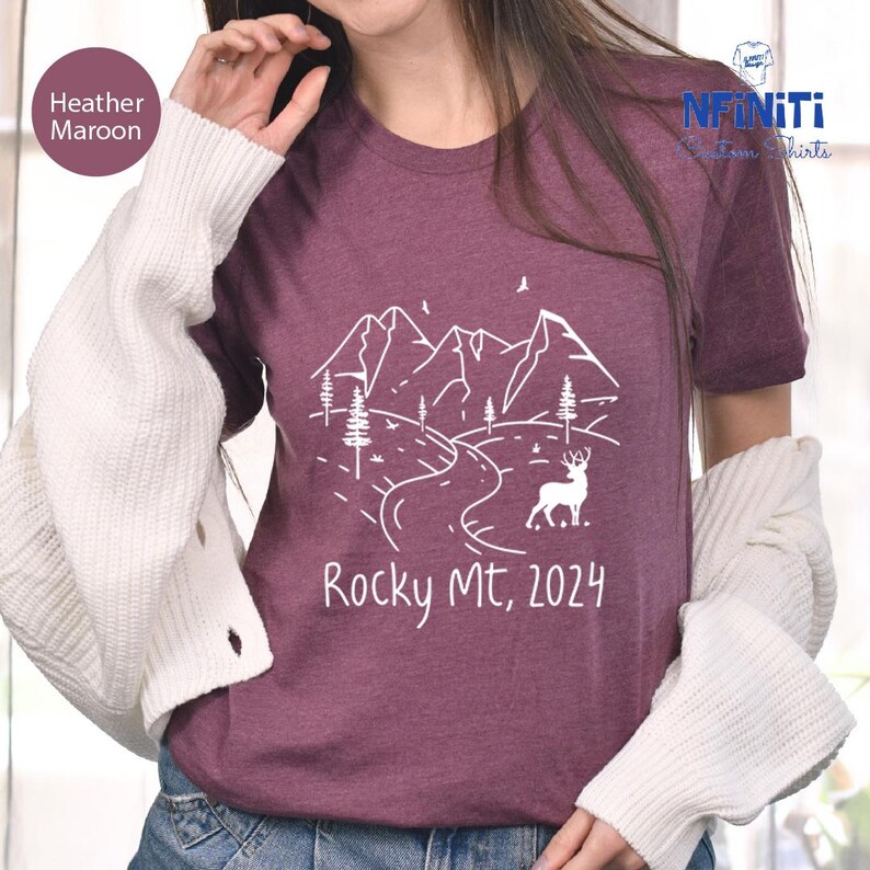 a woman wearing a t - shirt with a mountain scene on it