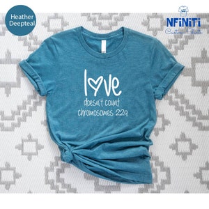 May include: A heather deepteal t-shirt with white text that reads "Love doesn't count chromosomes 22q".