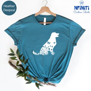 May include: A teal blue t-shirt with a white silhouette of a dog with flowers and butterflies inside the outline. The text "NFINITI Custom Shirts" is in the top right corner of the image.