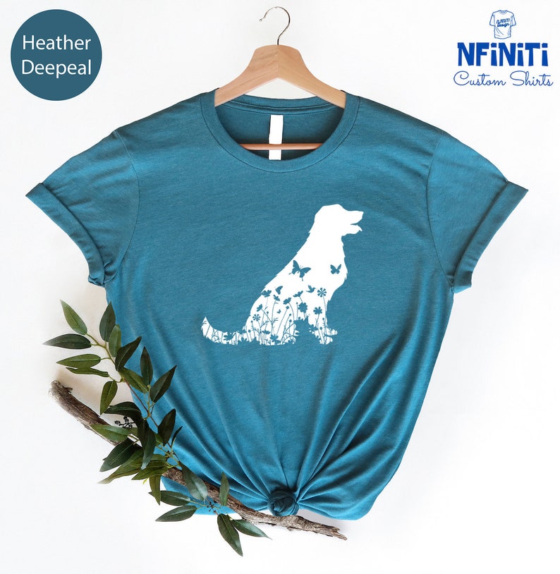 May include: A teal blue t-shirt with a white silhouette of a dog with flowers and butterflies inside the outline. The text "NFINITI Custom Shirts" is in the top right corner of the image.