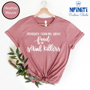 May include: A heather mauve t-shirt with the text "Probably thinking about food or serial killers" in white.