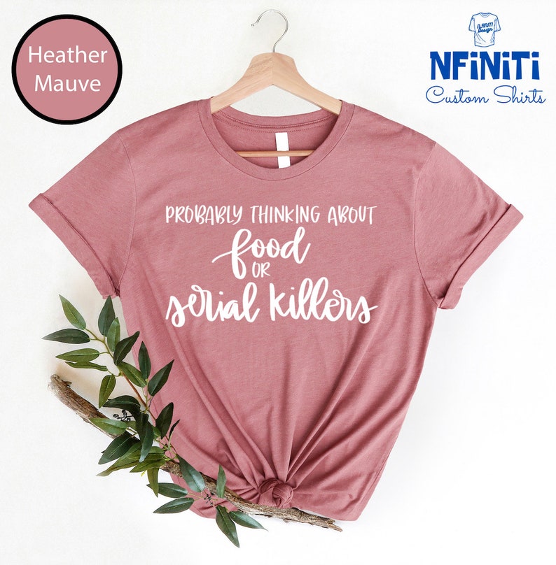 May include: A heather mauve t-shirt with the text "Probably thinking about food or serial killers" in white.