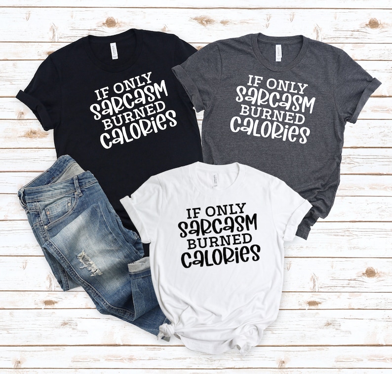 May include: Three t-shirts with the text "If only sarcasm burned calories" in black lettering on a white, dark grey, and black background.