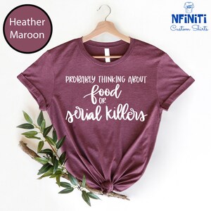 May include: A heather maroon t-shirt with the text "Probably thinking about food or serial killers" printed in white.
